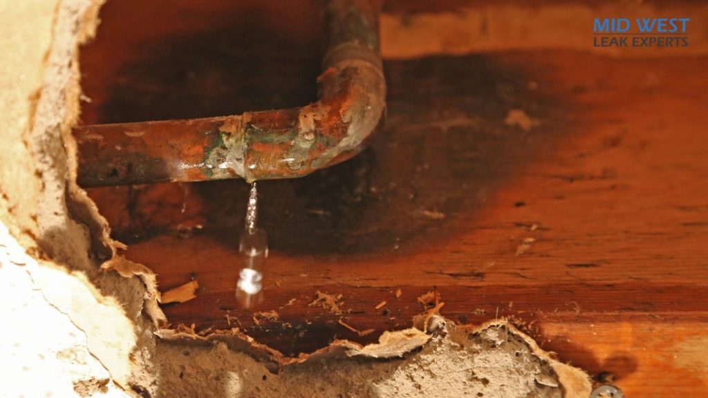water dripping from a pipe into a hole in a wall
